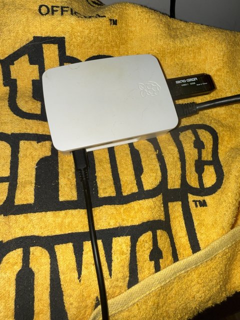 A Raspberry Pi in a white case with a USB stick plugged in, sitting on a yellow towel